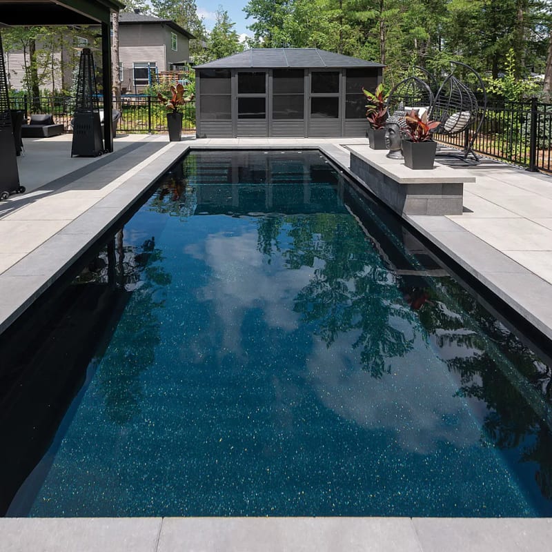 Elegant dark fiberglass pool with screen house in compact backyard