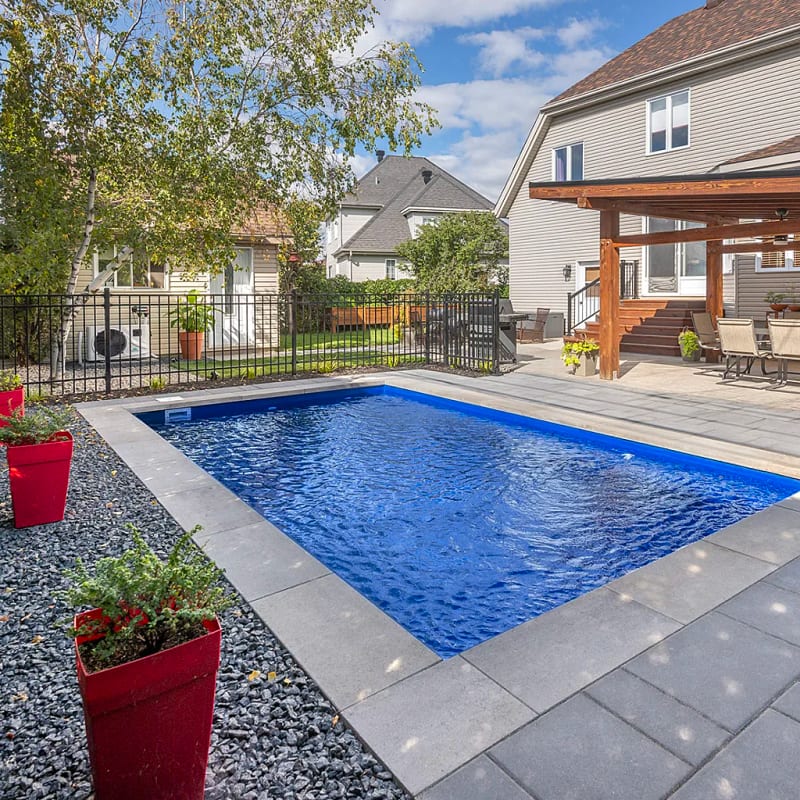 Fiberglass pool in a suburban backyard with pergola and patio