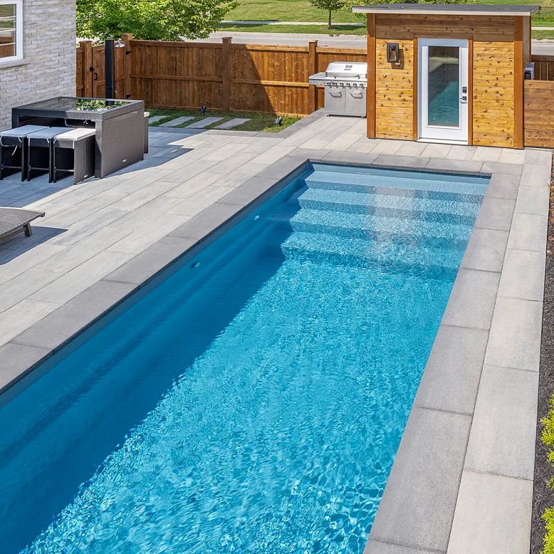 Modern fiberglass pool with clean lines and stone coping