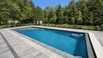 Rectangular fiberglass pool with a stone patio