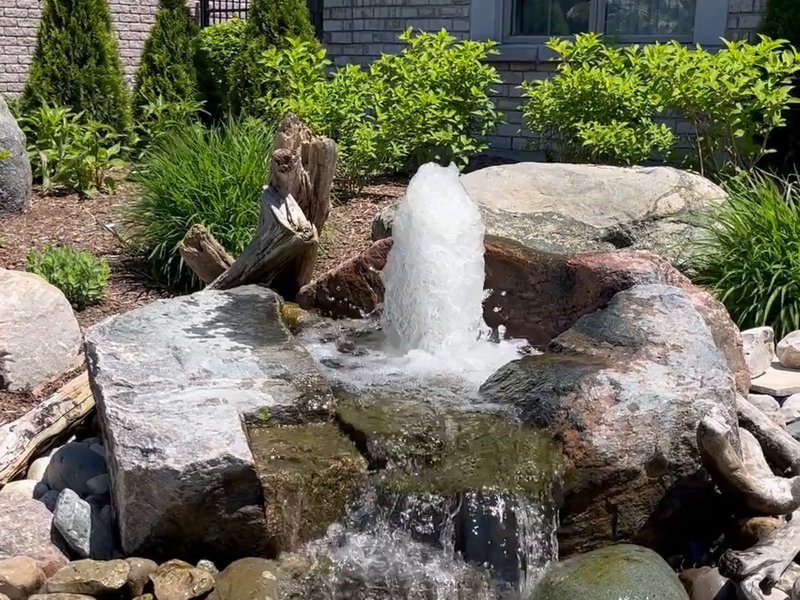 Bubbling rock water feature in a front yard rock garden
