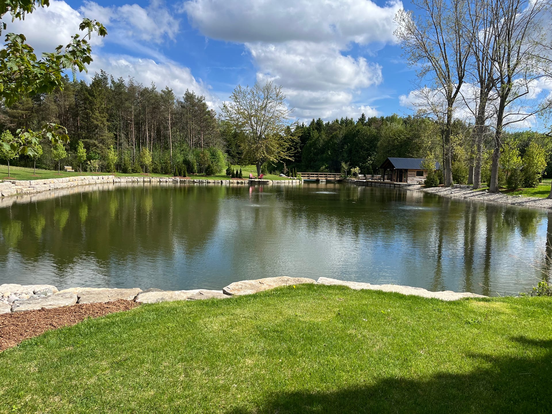 Large natural pond with a lawn and stone shoreline