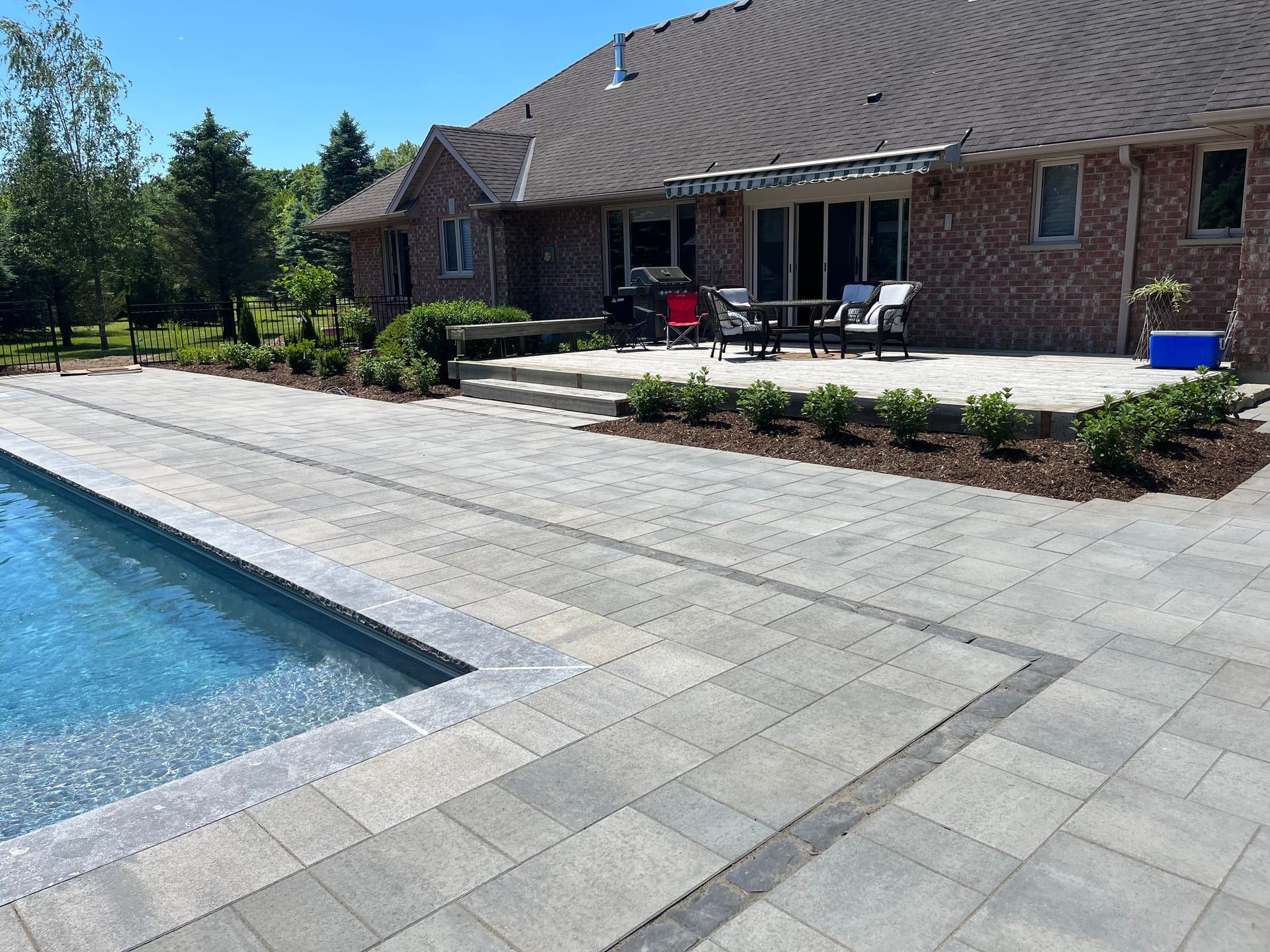Custom stone patio and landscaping around fiberglass pool in Komoka Ontario